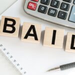 Word,Bail,On,Wooden,Cubes,On,Blue,Background.,The,Inscription